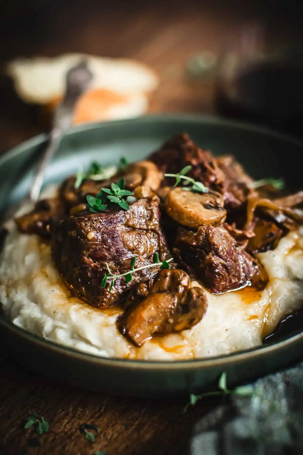 Braised short ribs over mashed potatoes in a green bowl.