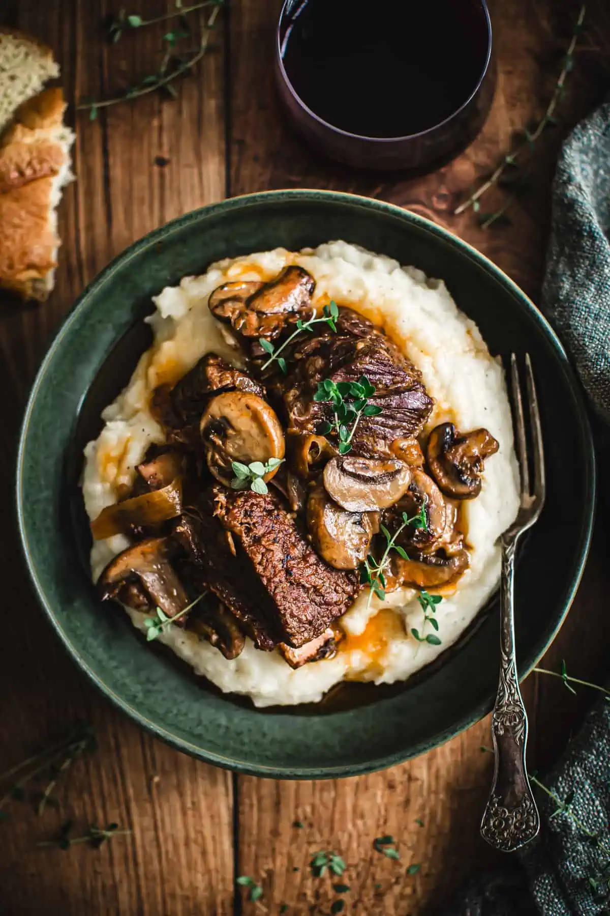 Braised short ribs over mashed potatoes in a green bowl.