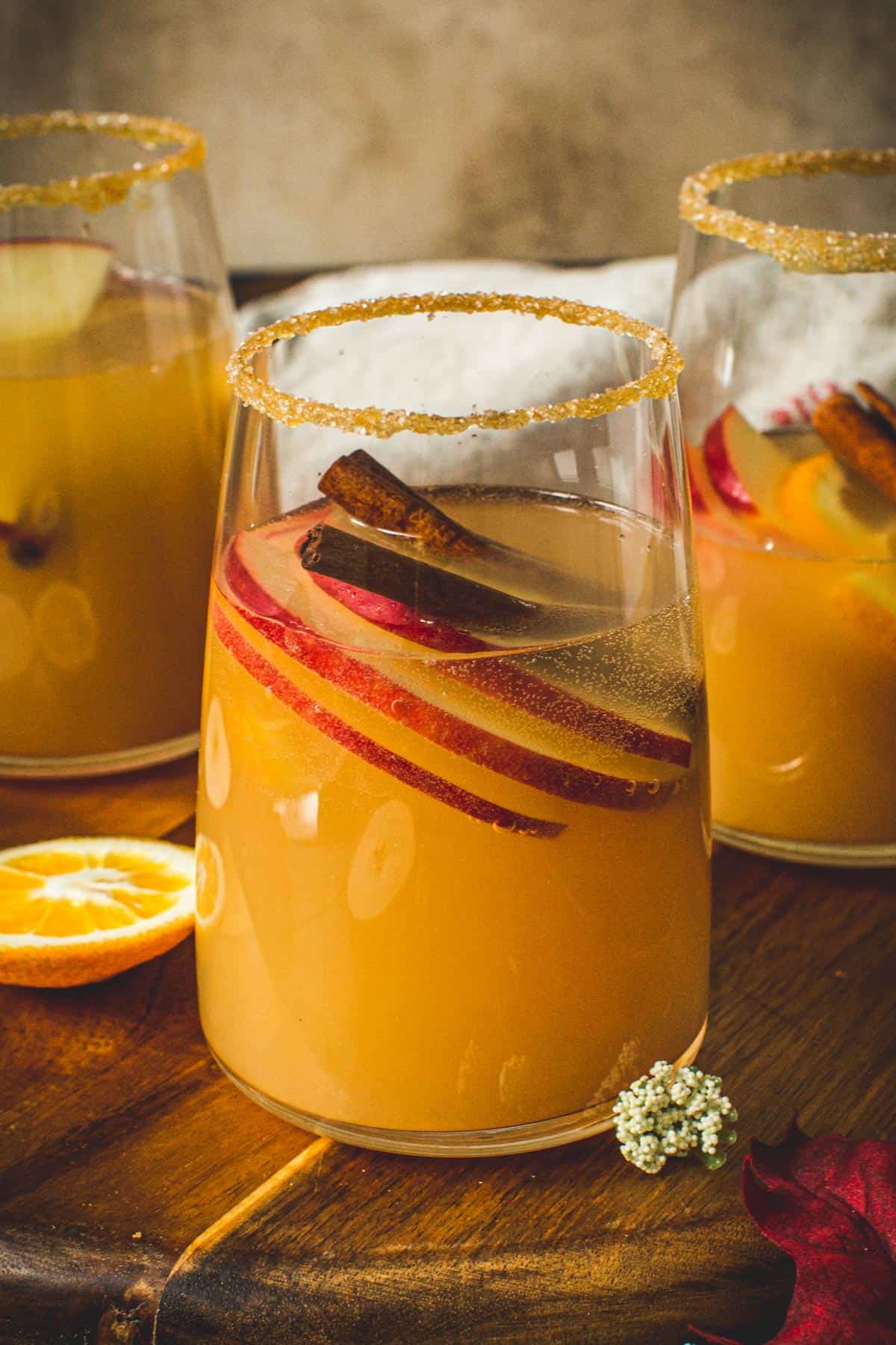 Caramel Apple Sangria in a glass with a sugared rim and cinnamon sticks and apple slices for garnish.