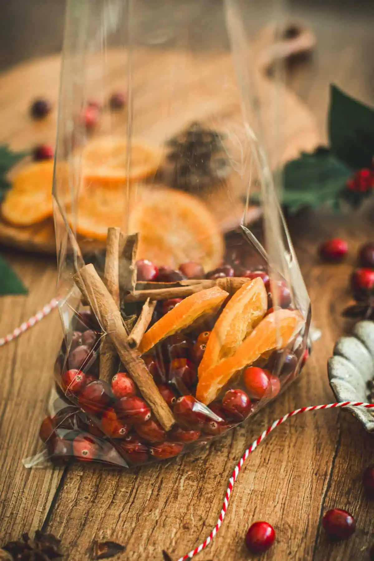 Fresh cranberries, dried orange slices, and cinnamon sticks in a cellophane bag for making Christmas potpourri.