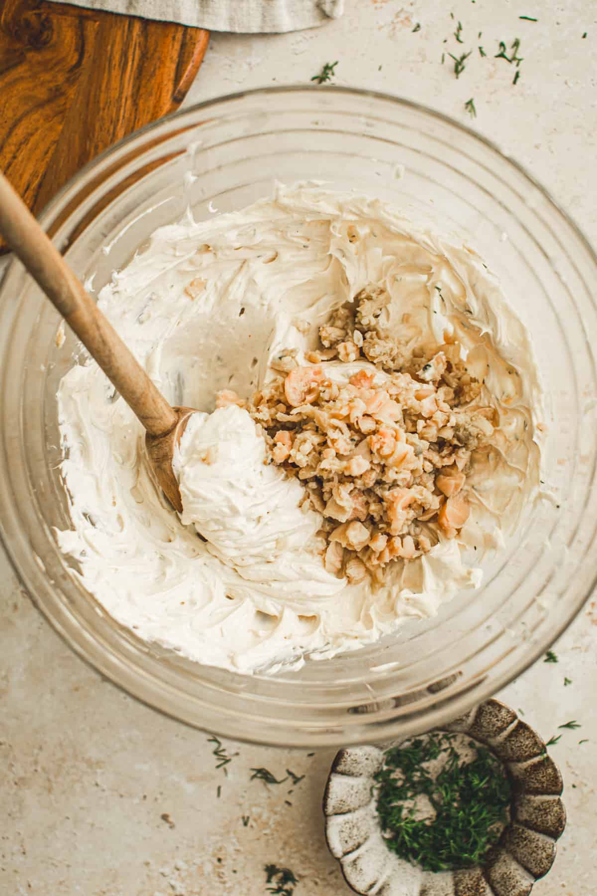 Drained minced clams added to the dip in a mixing bowl ready to be folded in.