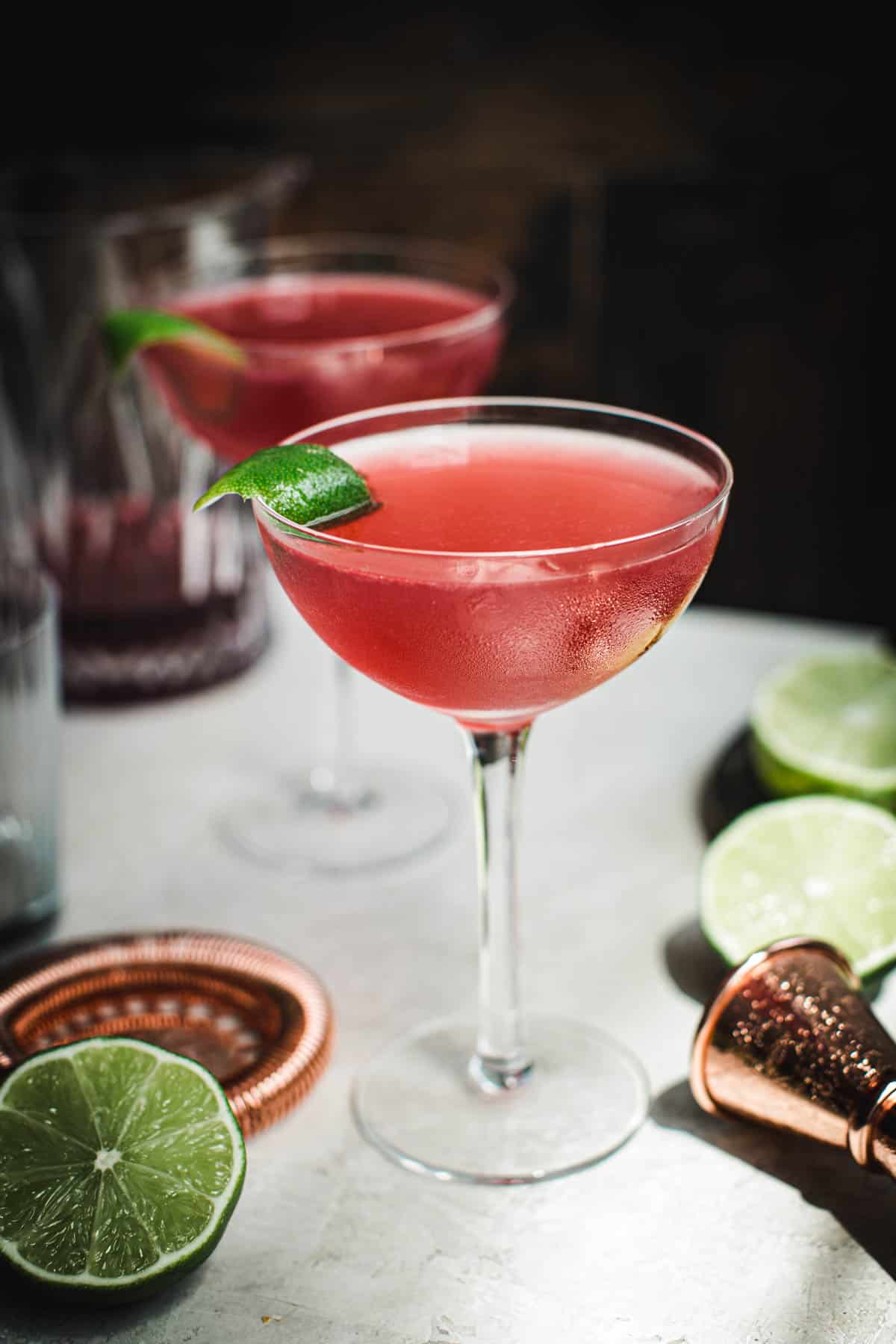 Cosmopolitan cocktail with a lime peel for garnish.