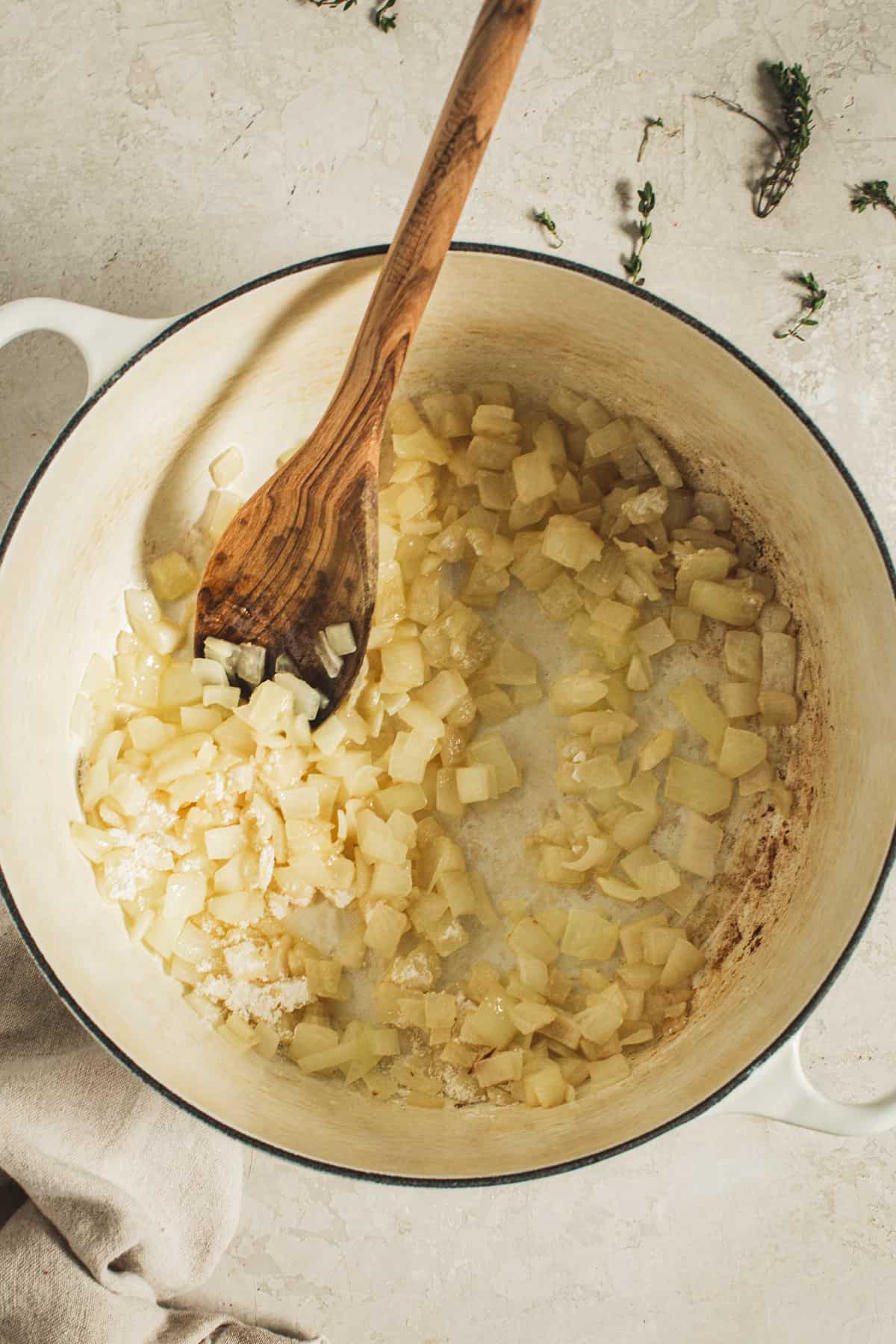 Flour sprinkled on top of sautéed onions in a pot for making creamed corn.