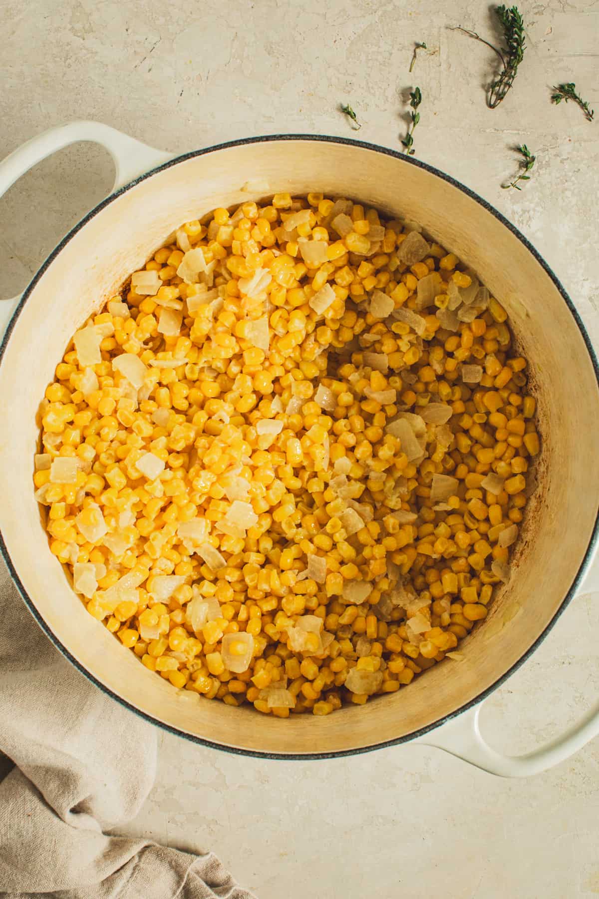 Corn mixed with sautéed onions for making creamed corn.