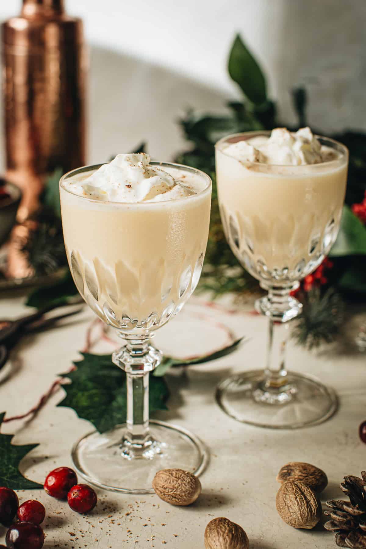 Eggnog martinis topped with whipped cream and nutmeg in crystal goblet glasses.