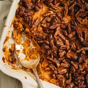 Healthy sweet potato casserole in a square baking dish with some scooped out and a serving spoon in it's place.