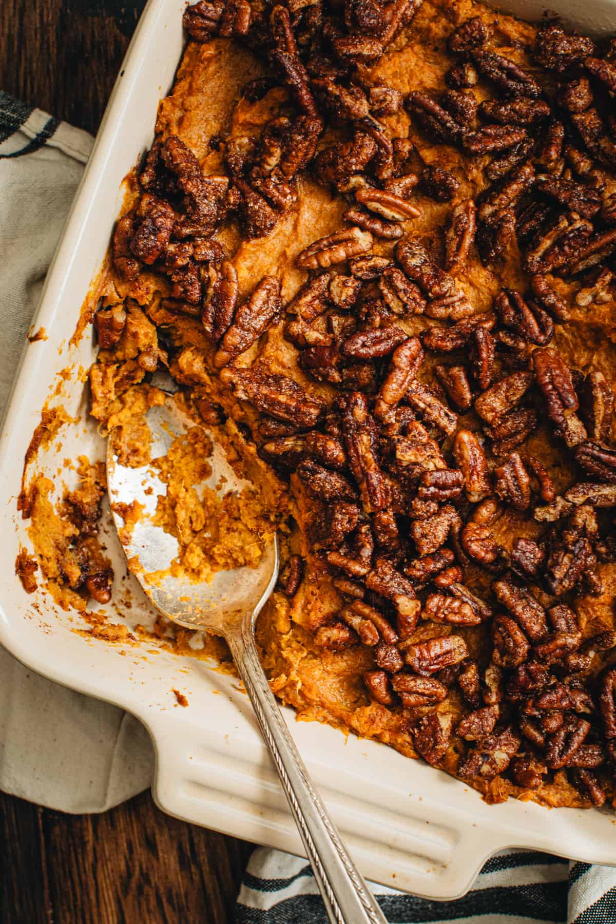 Healthy sweet potato casserole in a square dish with some scooped out using a silver serving spoon.