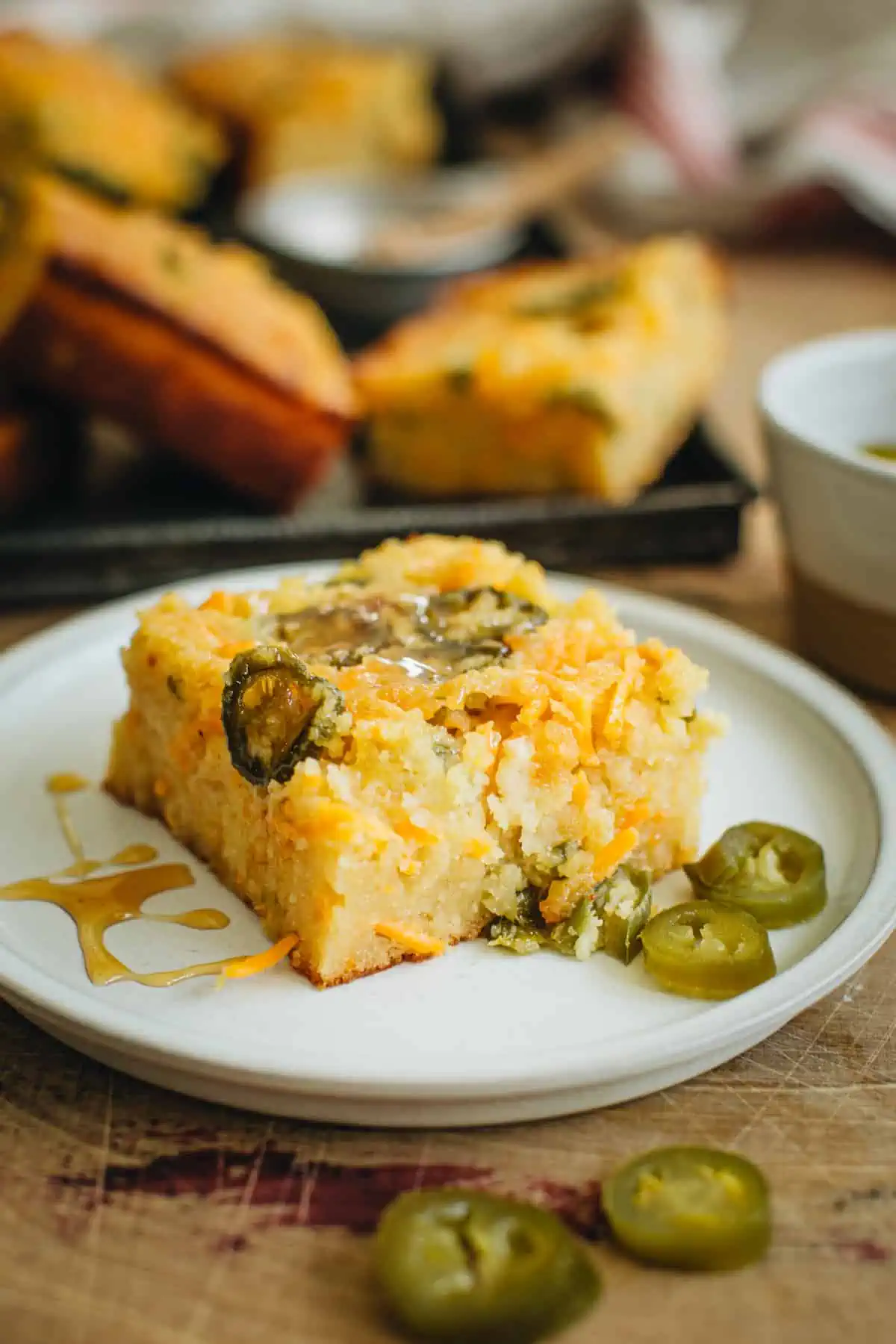 Slice of jalapeño cornbread with honey drizzled on top.