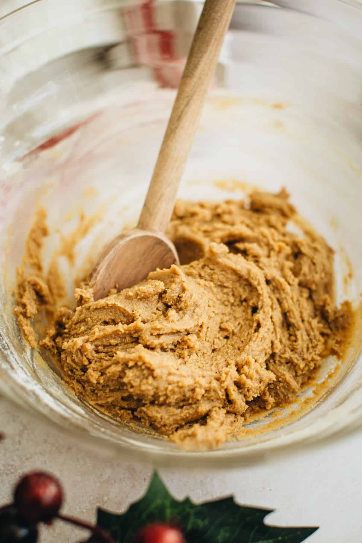 Molasses crinkle cookie dough in a mixing bowl with a wooden spoon.