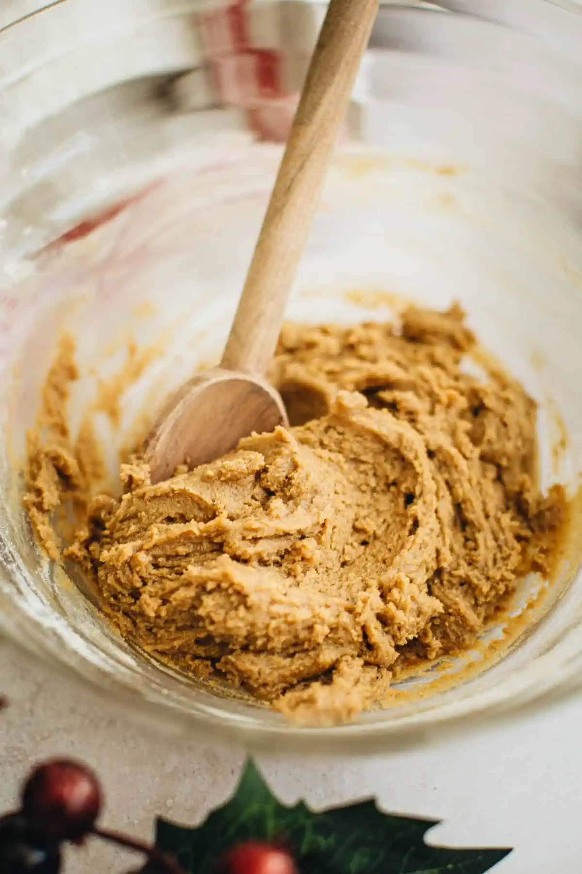 Molasses crinkle cookie dough in a mixing bowl with a wooden spoon.