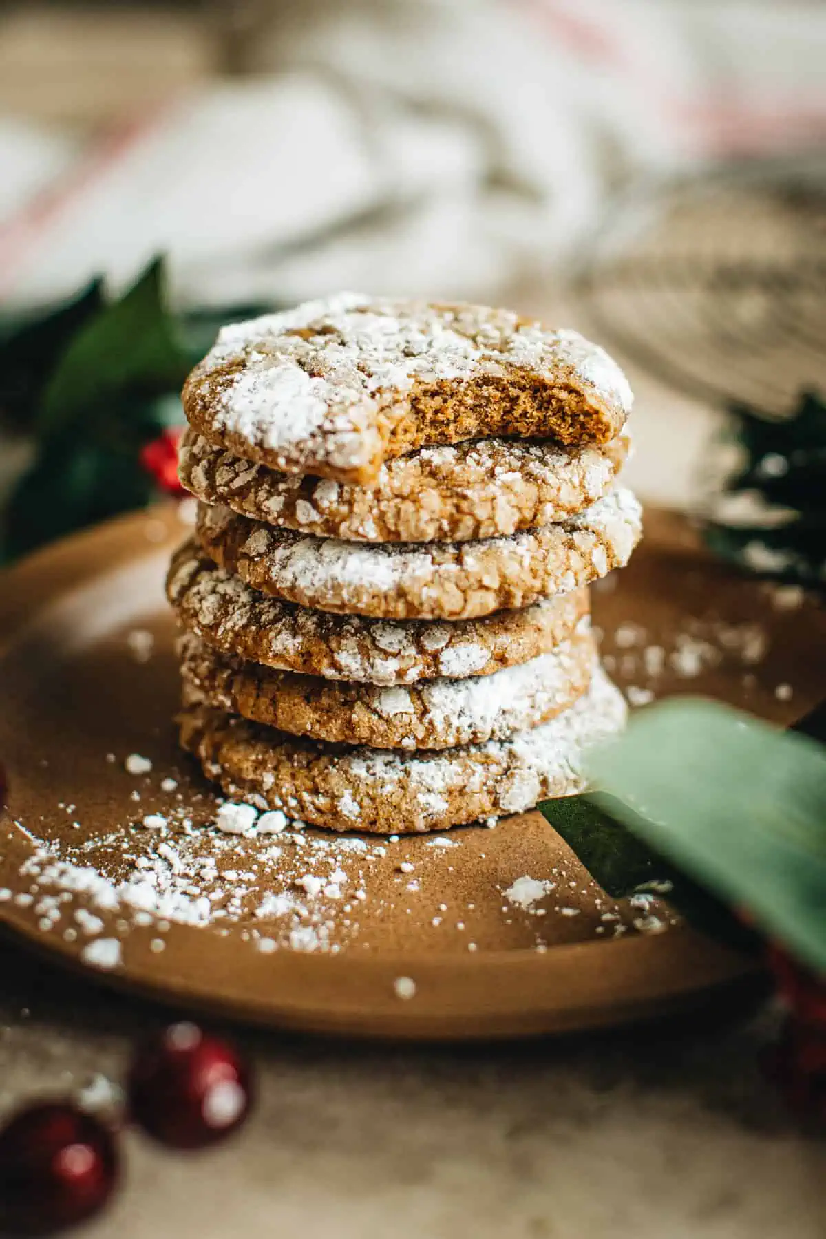 Stack of Molasses Crinkle Cookies on a brown plate with a bite taken out of the top cookie.