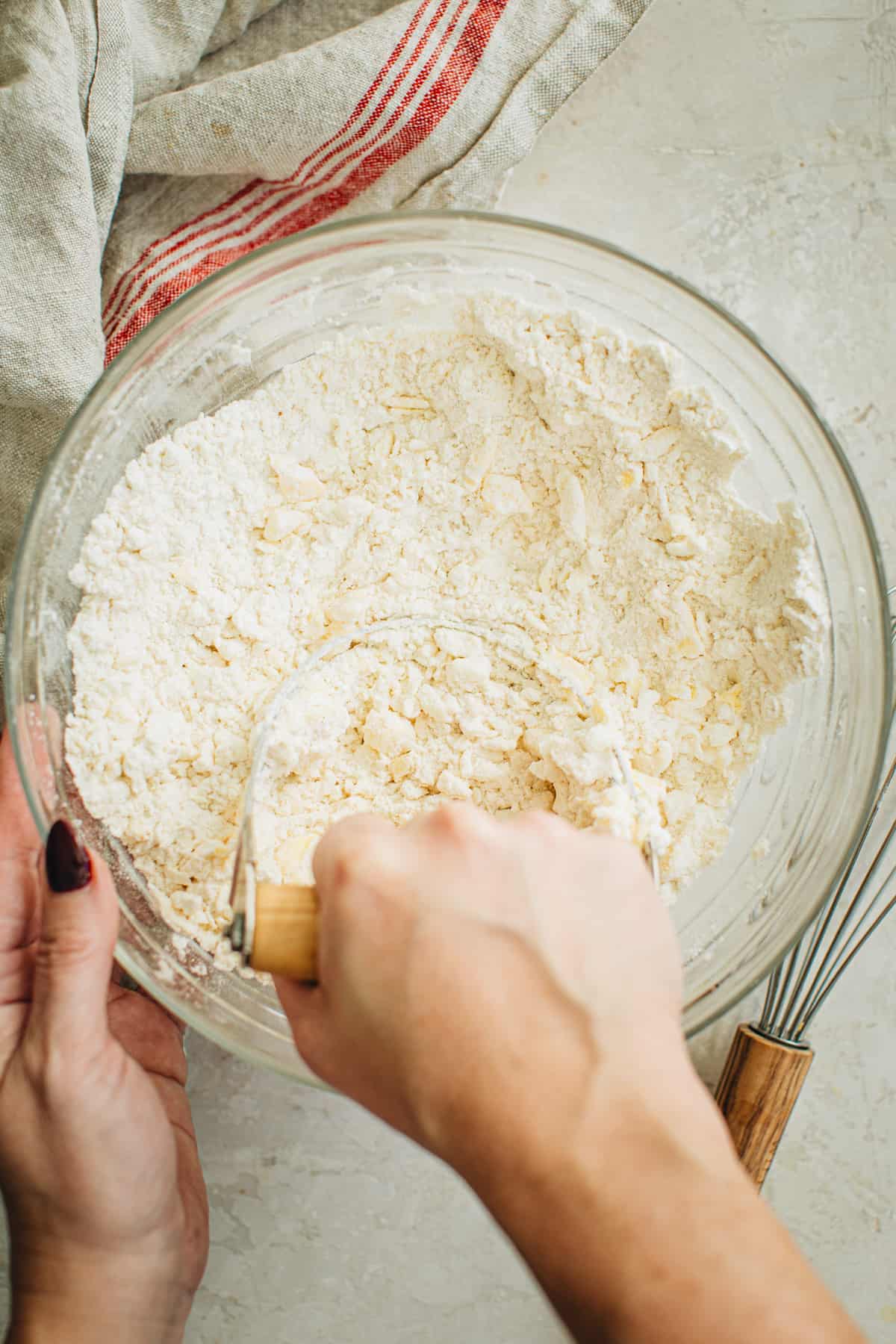 Using a pastry cutter to cut the butter and shortening into the flour and salt for making a pie crust with shortening.