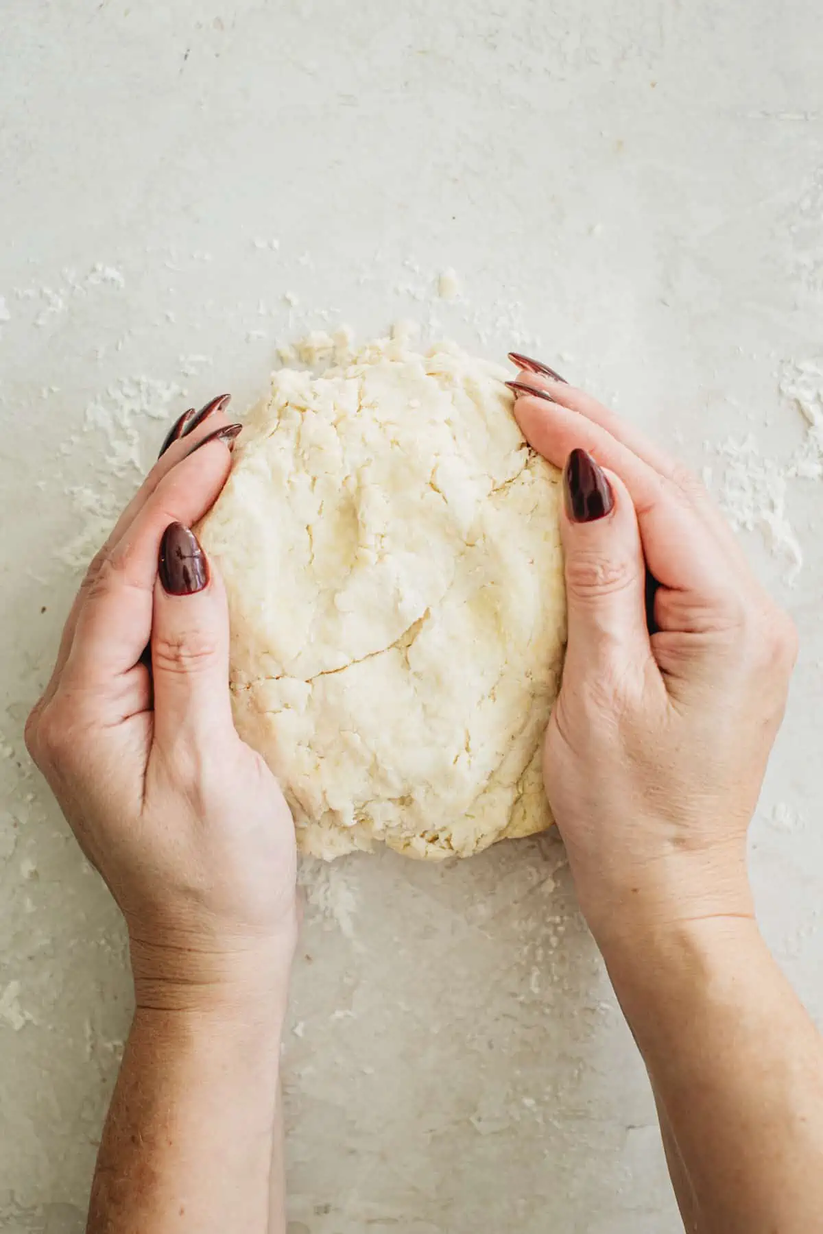 Forming the pie dough using hands for a pie crust with shortening.