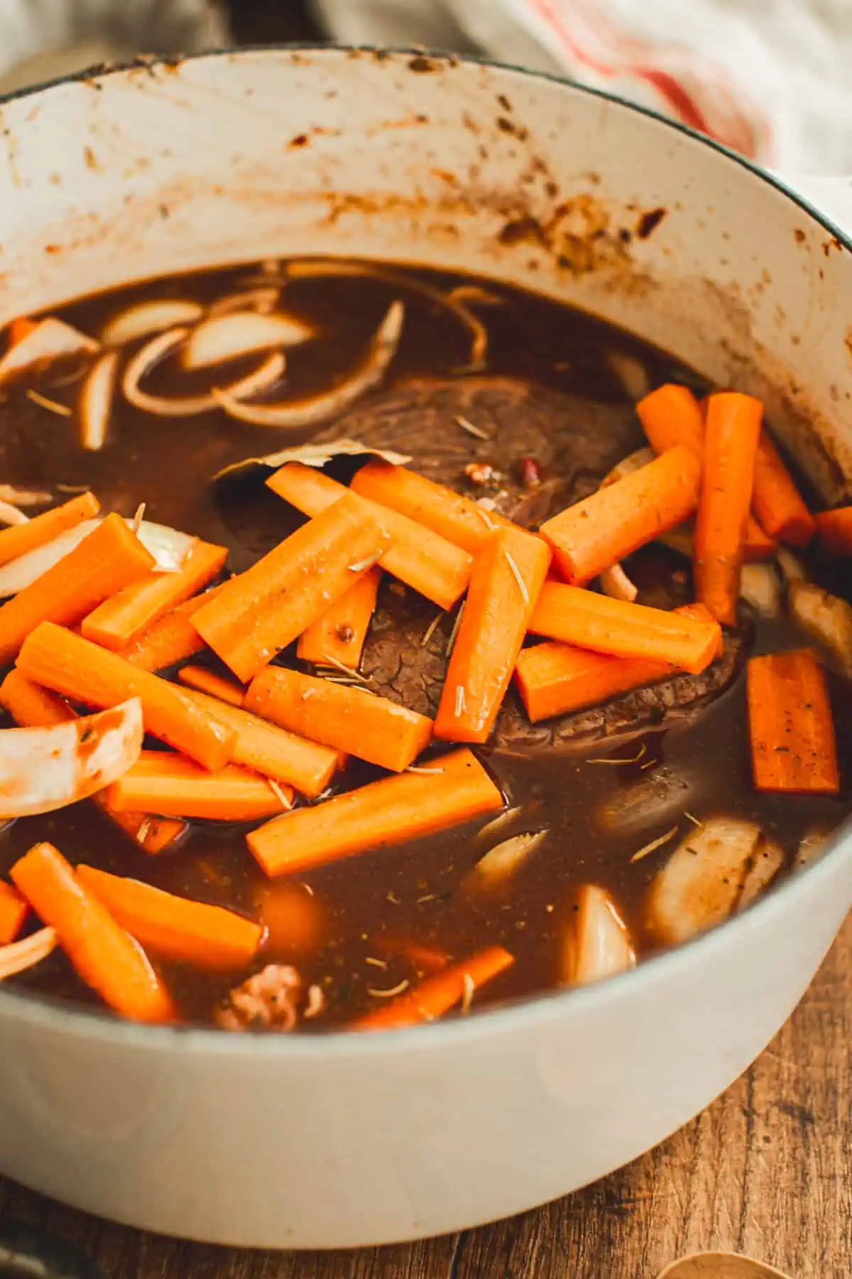 Onions, carrots, and liquid added to the pot roast before cooking it.