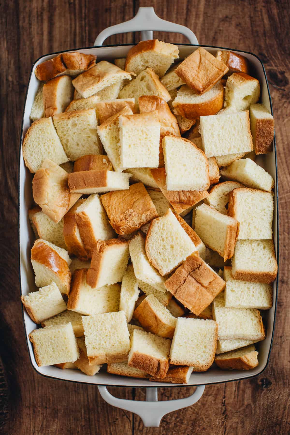 Cut up pieces of bread in a casserole dish for making pumpkin French toast casserole.