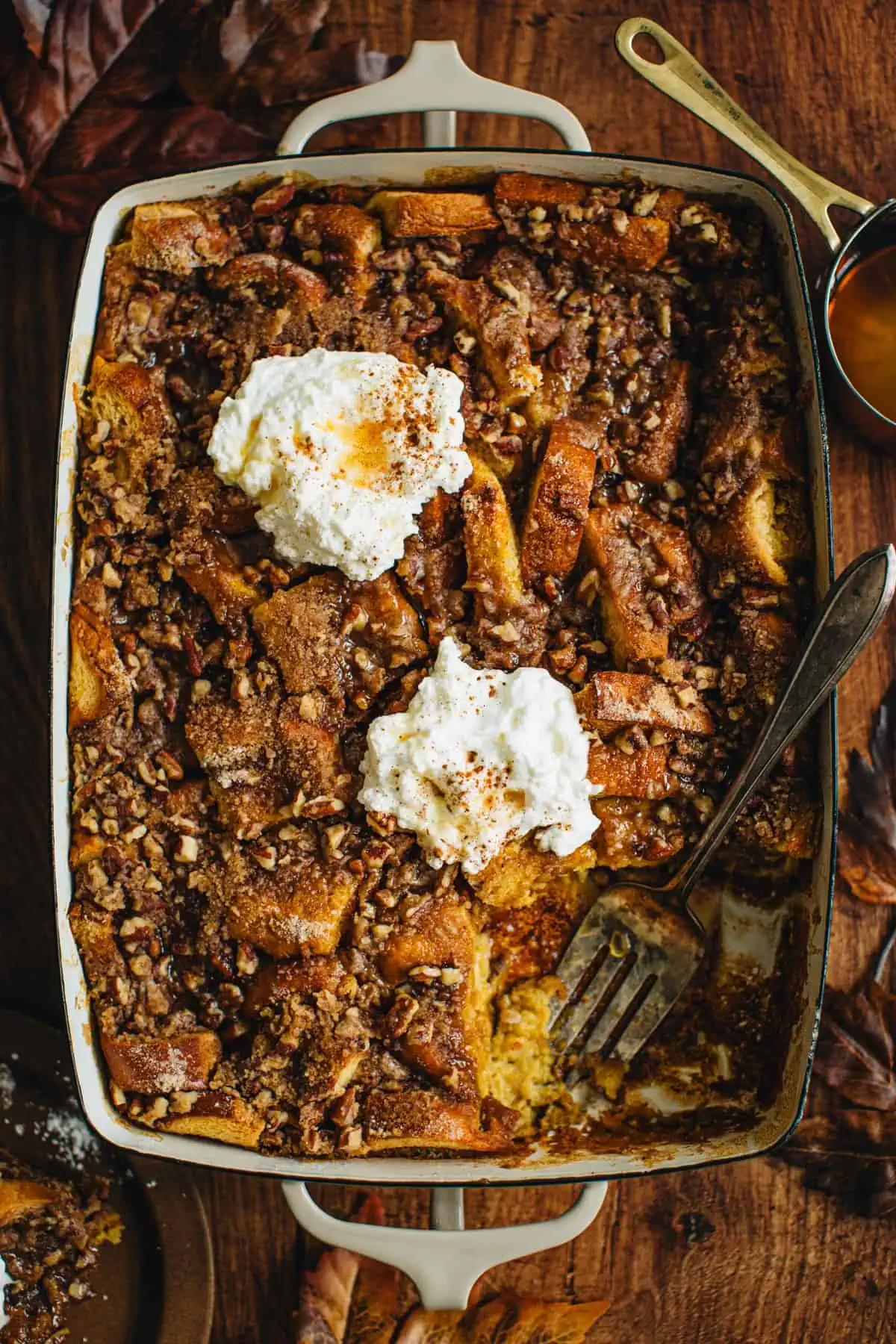 Pumpkin French Toast casserole in a casserole dish topped with whipped cream.