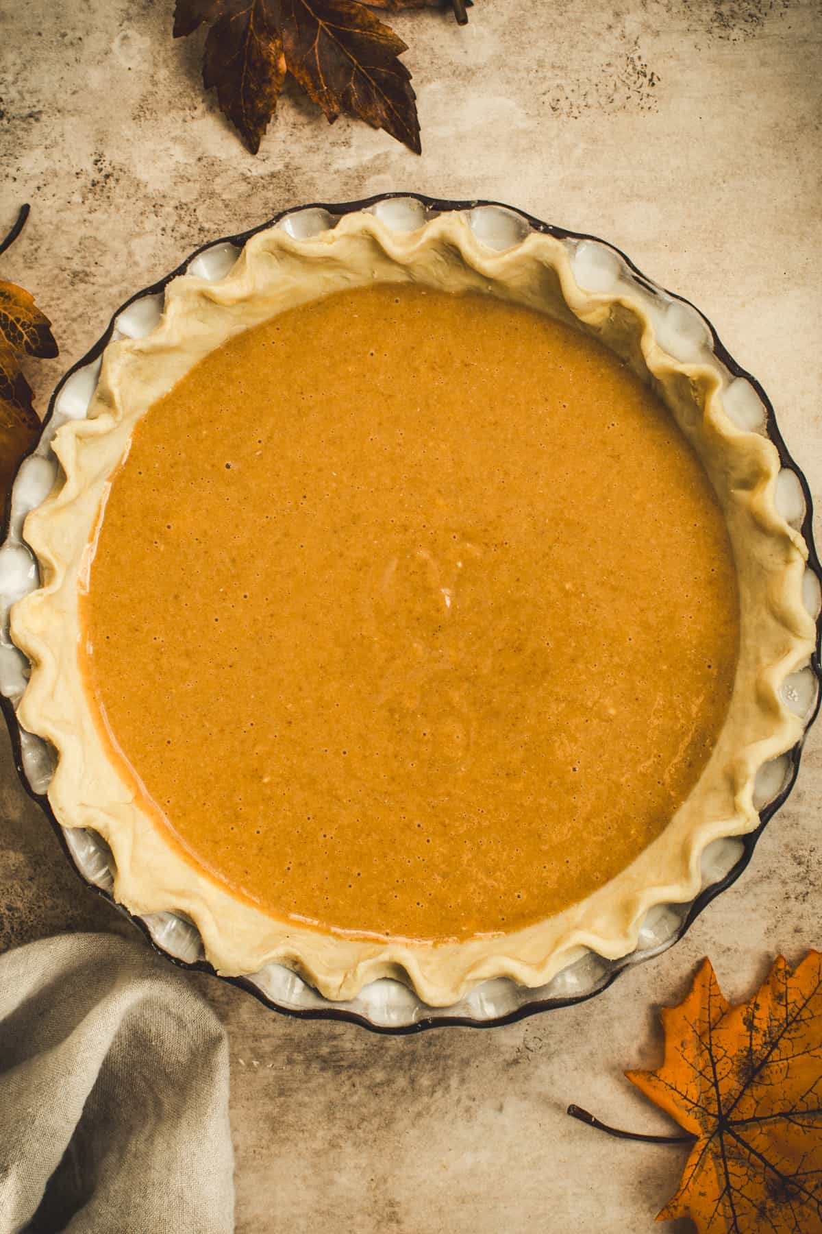 Pumpkin pie filling in an unbaked pie crust ready to bake.