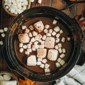 Pumpkin spice hot chocolate in a slow cooker topped with marshmallows.