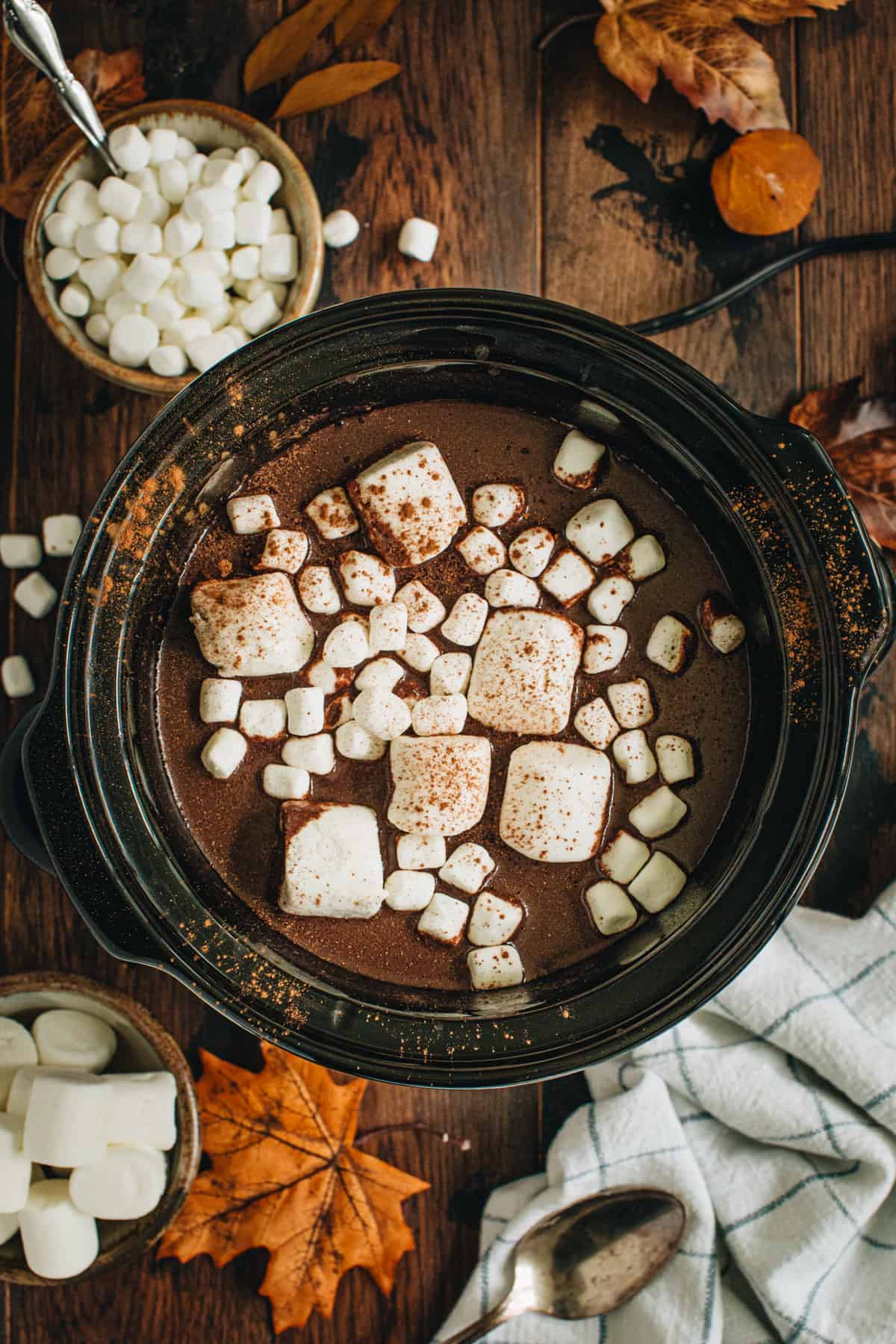Pumpkin spice hot chocolate in a slow cooker topped with marshmallows.