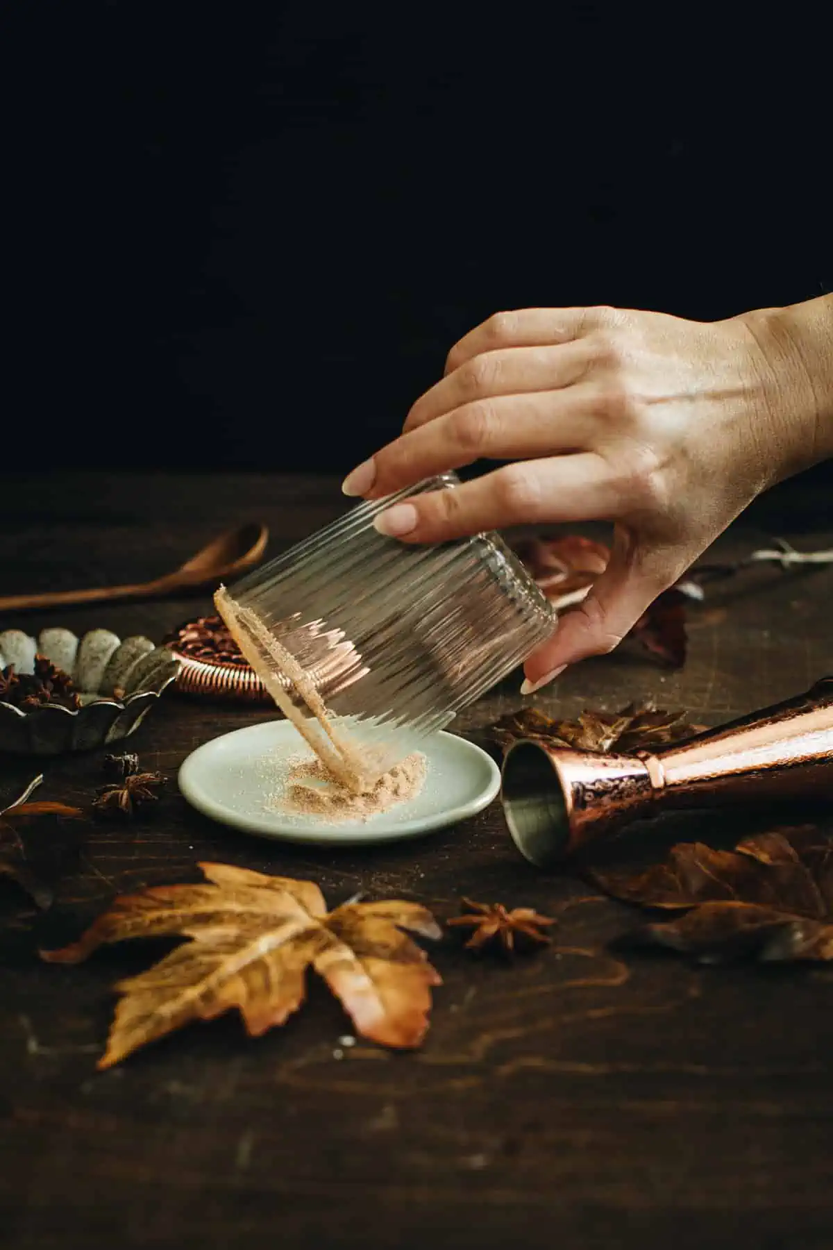 Dipping the rim of a glass in cinnamon sugar to coat it for a Pumpkin Spice Margarita.