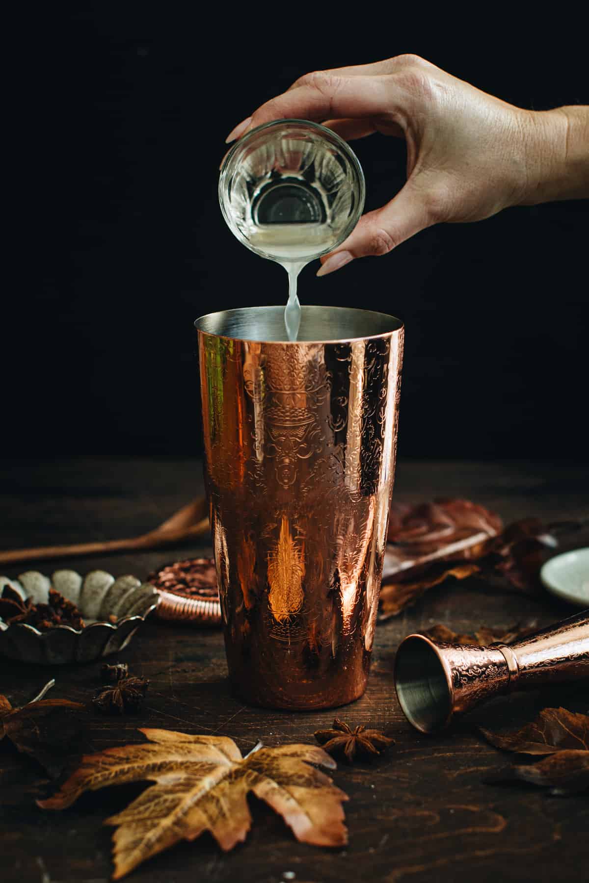 Pouring lime juice into a cocktail shaker for making a Pumpkin Spice Margarita.