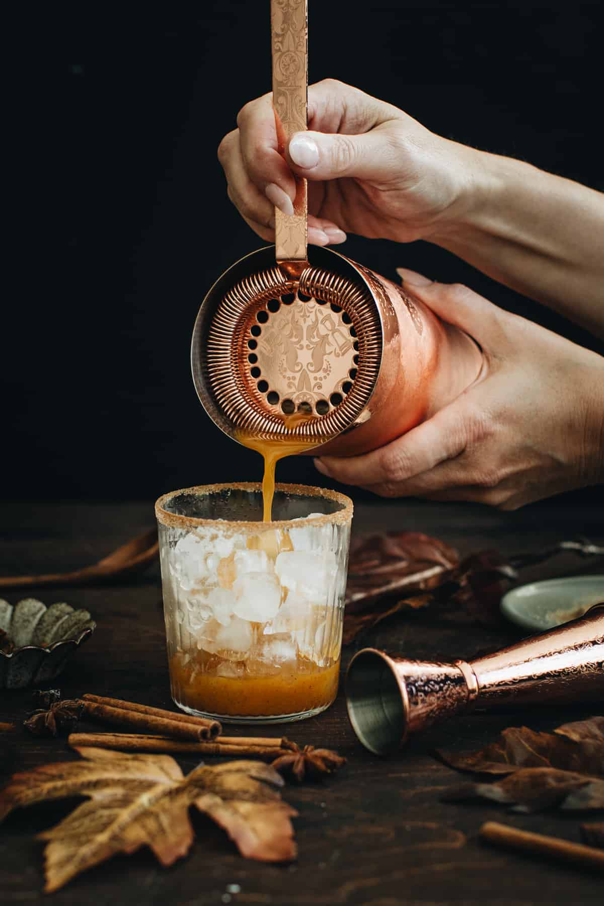 Straining a Pumpkin Spice Margarita over ice.
