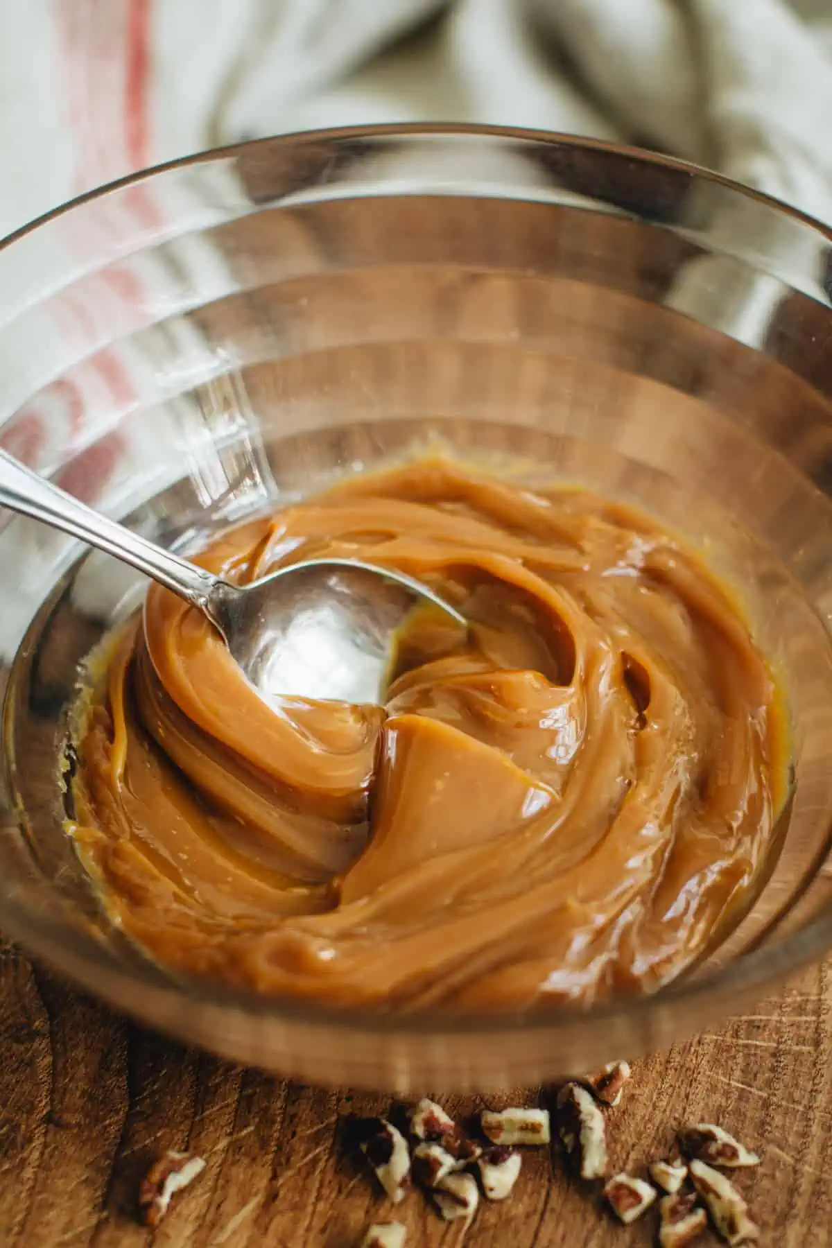 Caramel sauce in a mixing bowl with a spoon for making turtle cookies.