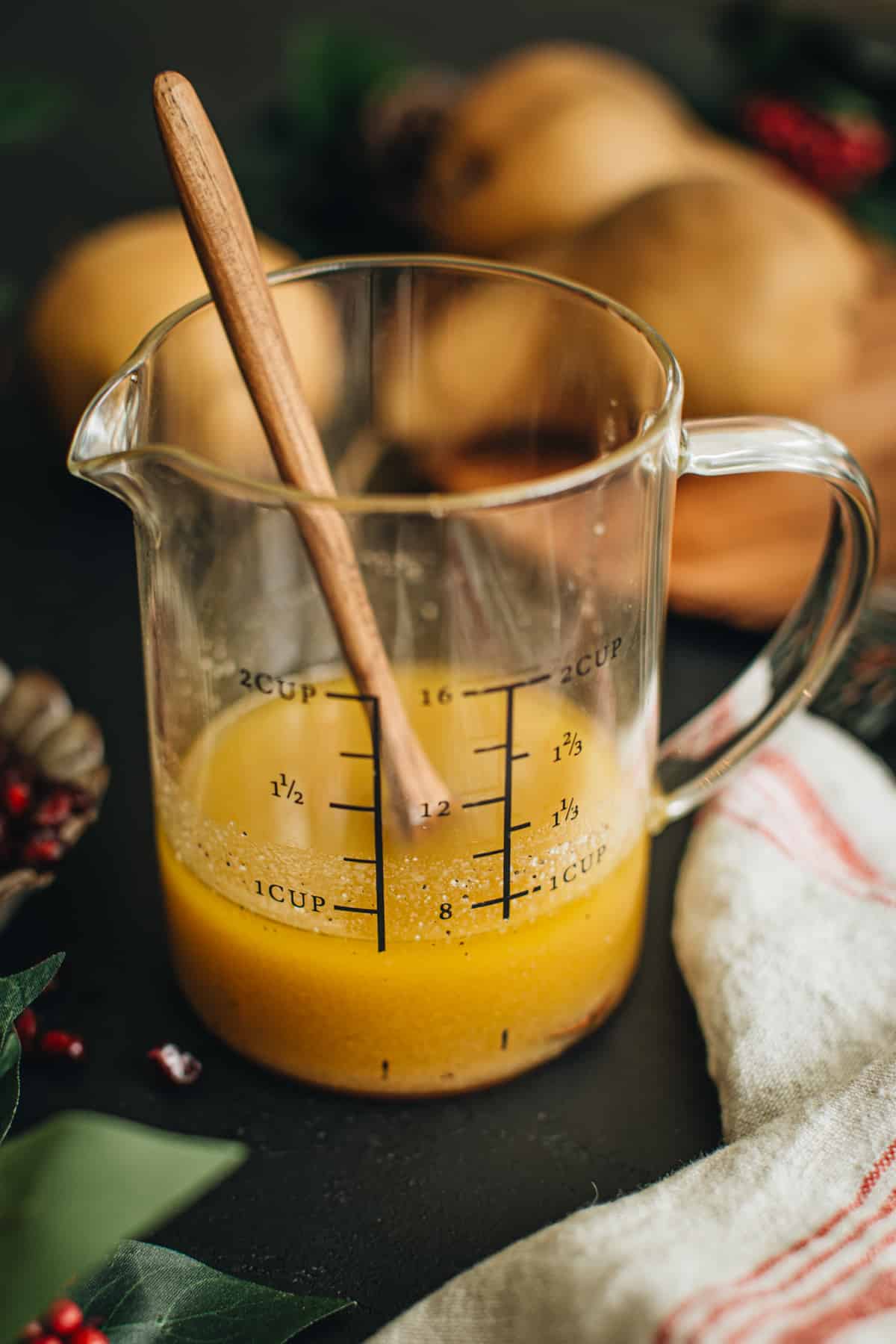 Homemade vinaigrette in a measuring cup ready to drizzle on top of Christmas Salad.