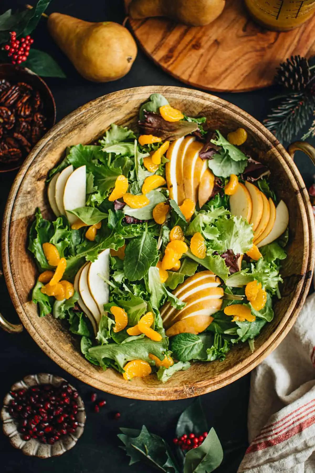 Mixed greens topped with sliced pears and mandarin oranges for preparing Christmas Salad.