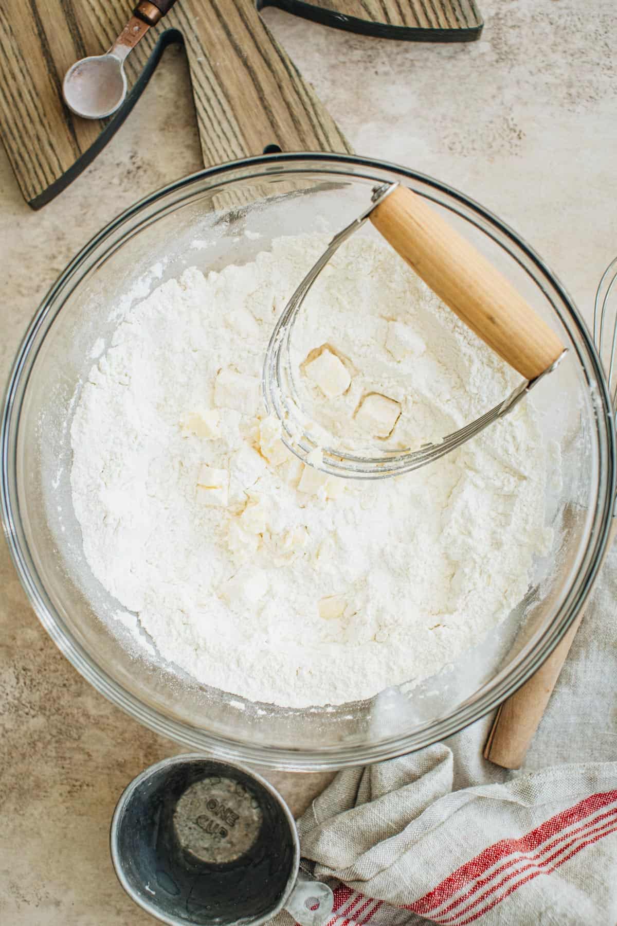 A pastry cutter, cutting butter cut into cubes into the flour mixture for making English scones.