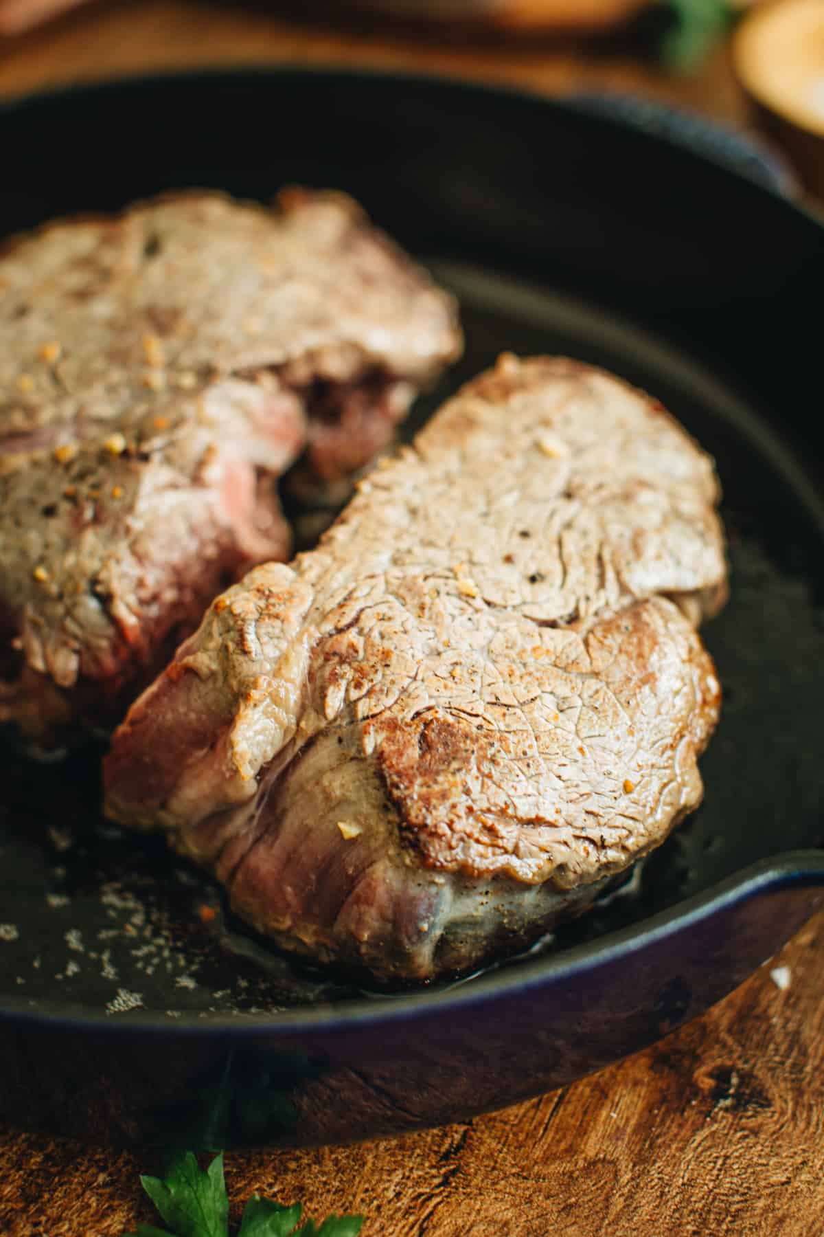 Seared cast iron filet mignon in a skillet.