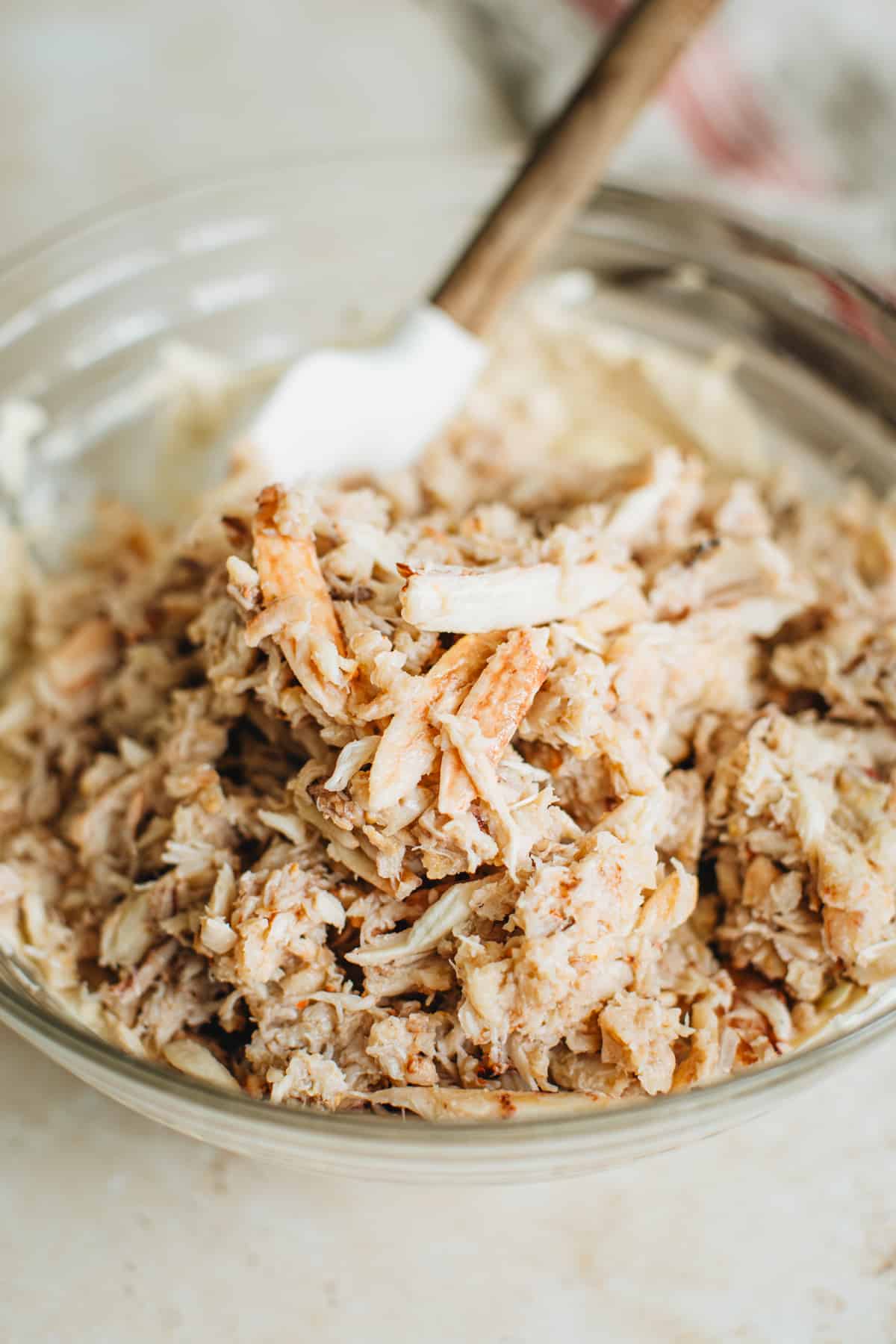 Fresh lump crab meat on top of the crab dip base mixture in a mixing bowl ready to be mixed.