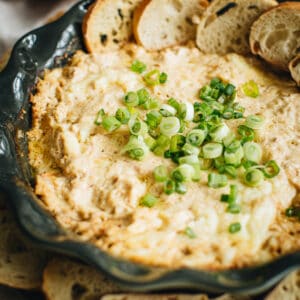Crab dip in a green pie dish topped with green onions.