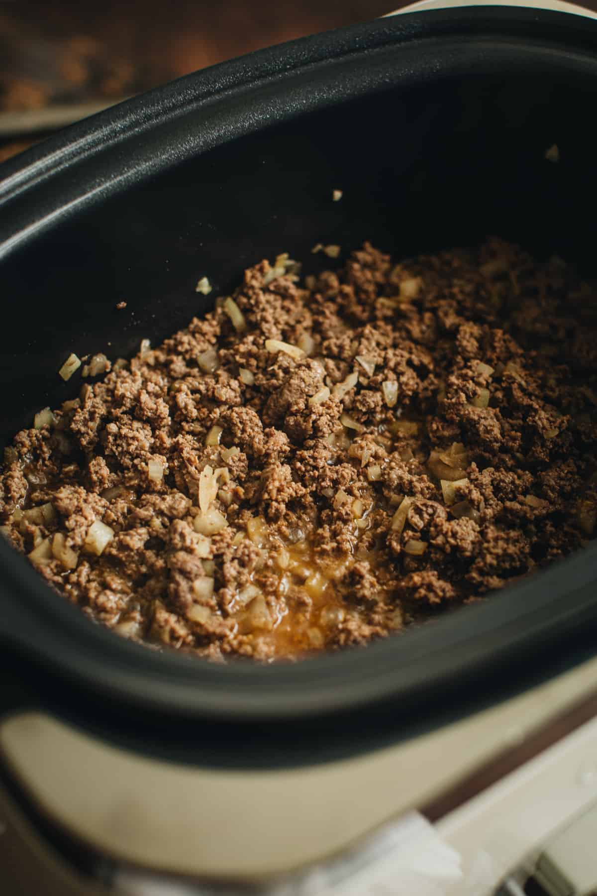 Brown meat and sautéed onions in a Crockpot for making Hamburger Helper. 