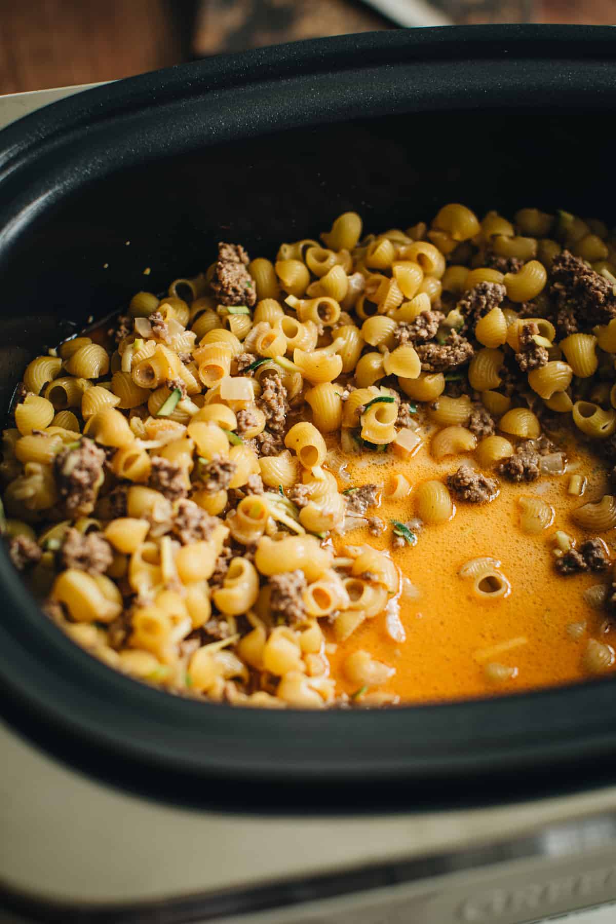 Hamburger helper ingredients in a Crockpot ready to cook.