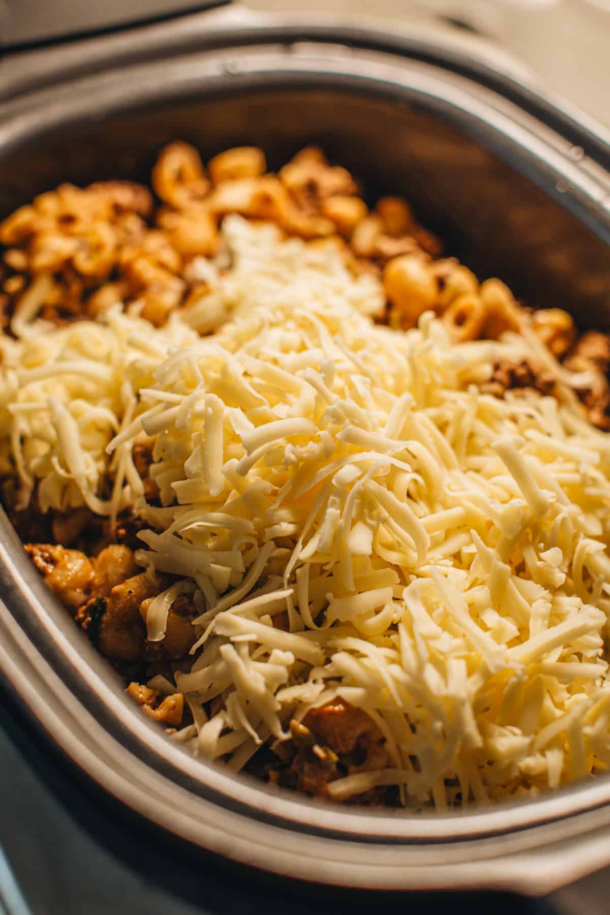 Shredded cheese on top of Crockpot hamburger helper in the Crockpot.