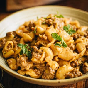 Crockpot hamburger helper in a bowl topped with fresh oregano.