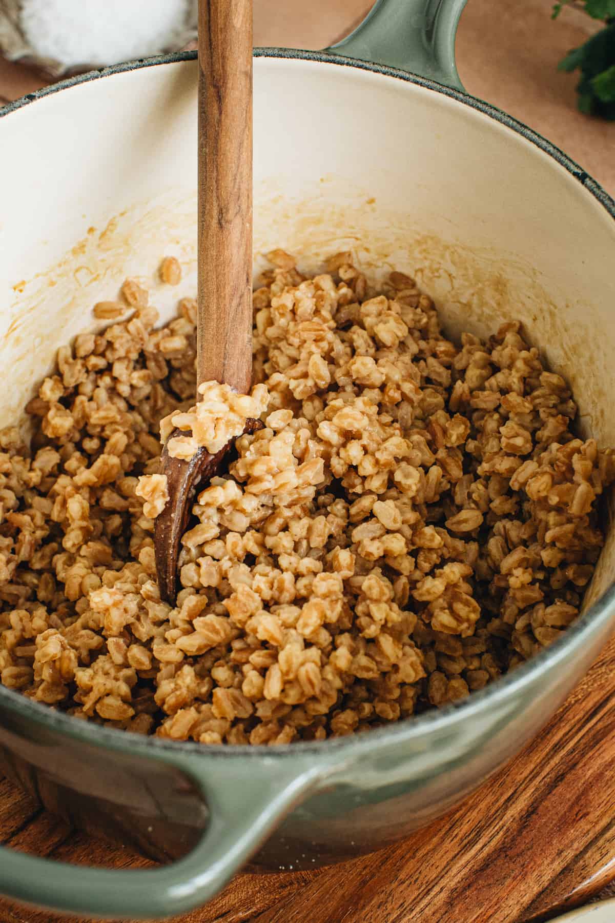 Cooked farro in a pot with a wooden spoon.