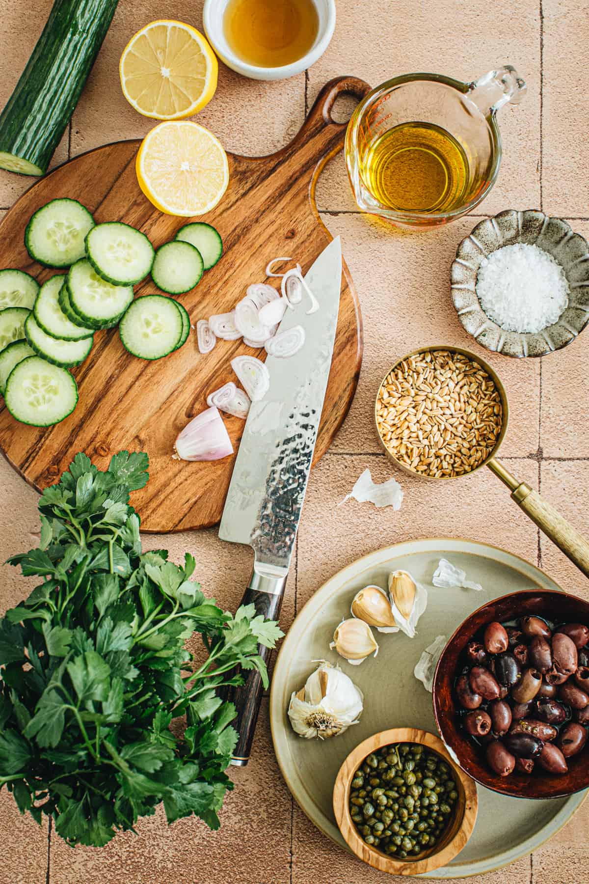 Ingredients for making farro salad with some in bowls and the fresh ingredients chopped on a cutting board.